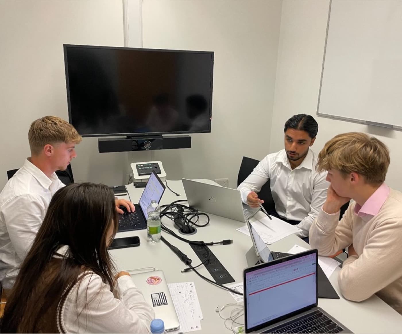 An Exe Consulting project team working together around a table covered in laptops and notes