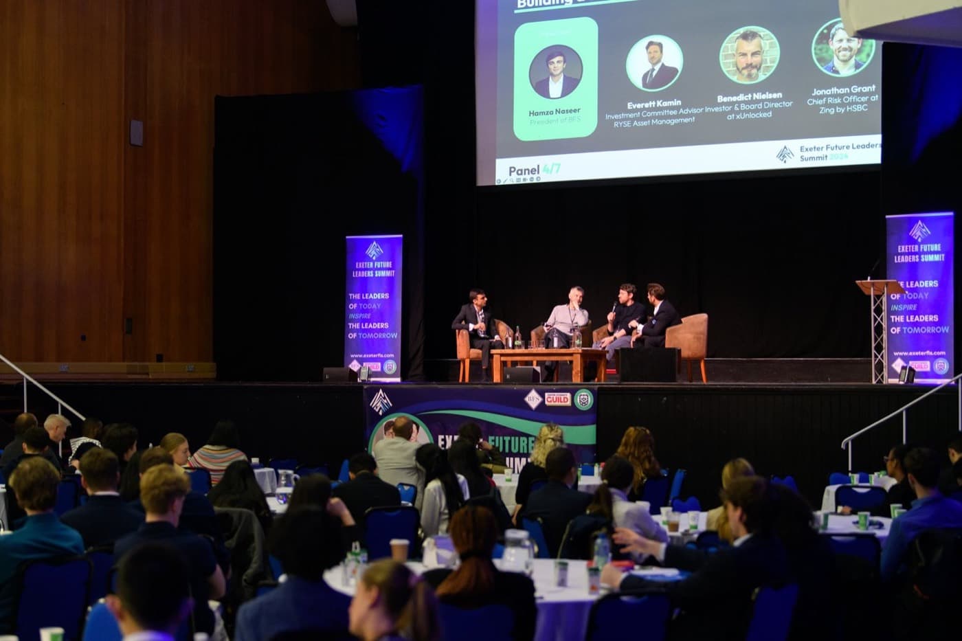 A panel discussion on stage at the Exeter Future Leaders Summit, in front of a full seated audience