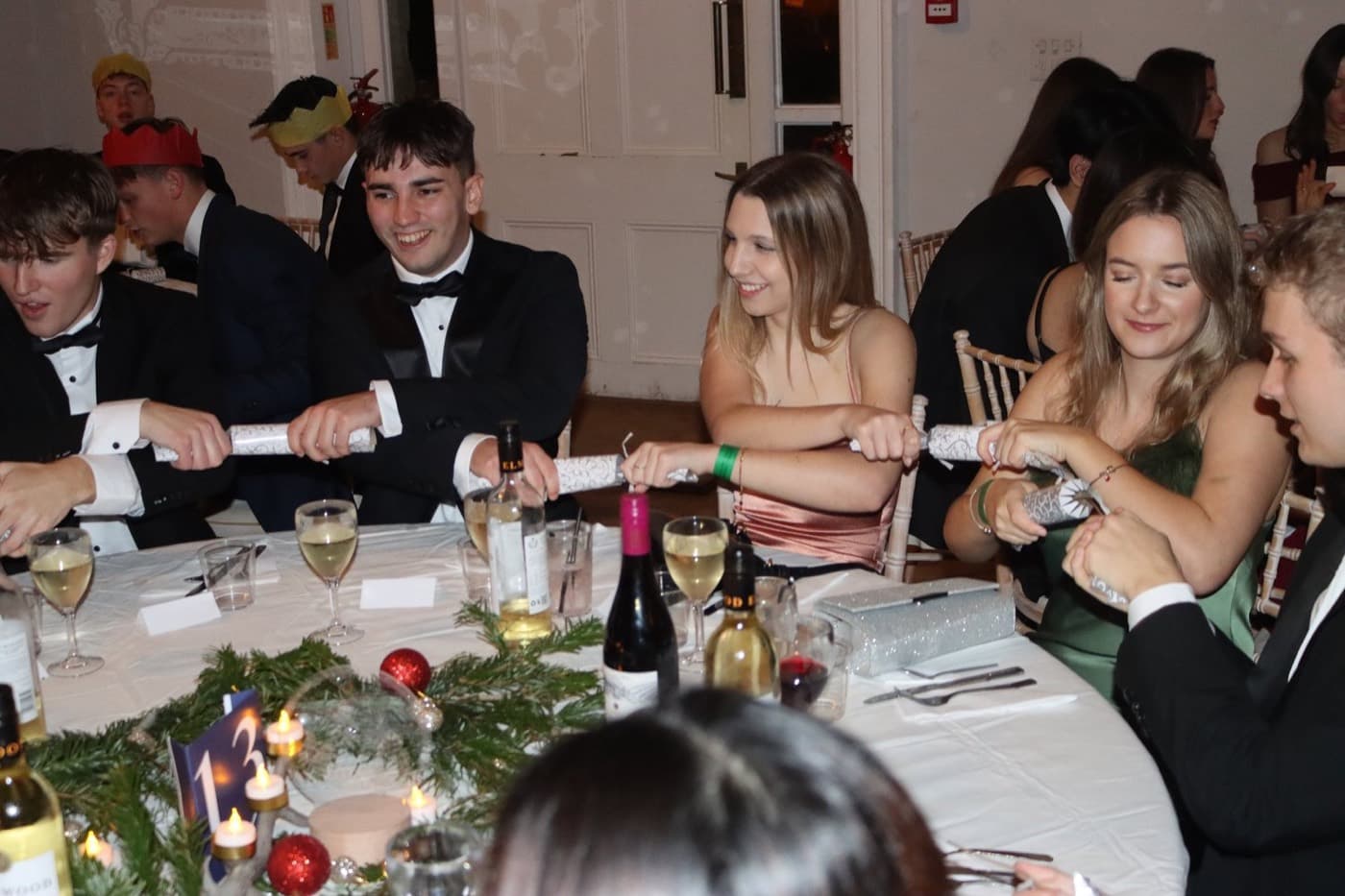 Members in black tie pulling crackers around a table at the Winter Ball